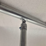 Uni‑Fit rail plate securing horizontal pipe to vertical post in installed application