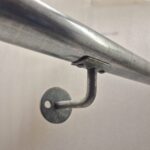 Uni‑Fit side mount base plate fixed to wall supporting horizontal handrail pipe